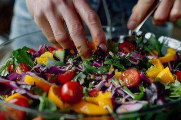 Fotobehang a person's hands tossing and dressing a colorful salad with homemade vinaigrette or citrus dressing © kashiStock
