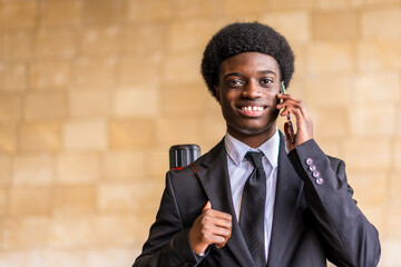Happy architect with afro hairstyle and suit talking by phone