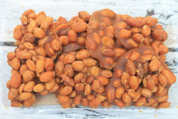 Indonesian snack called gulo kacang made from peanuts and brown sugar in mica plastic on the table