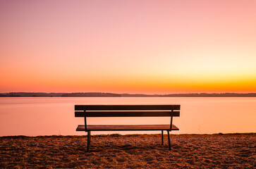 Fototapeta na wymiar Solitary Bench Overlooking a Tranquil Lake During a Sunset in Sweden