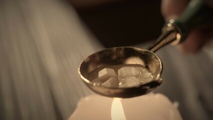 Female holding golden spoon with liquid. Close up shot of woman warms wax in a golden old spoon on...