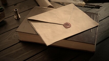 Shot of the table with old paper envelope. Vintage letter envelope laying on the old book sealed...