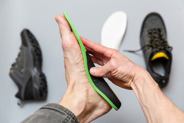 Close up of man hands fitting orthopedic insoles on a gray background. - 759564707