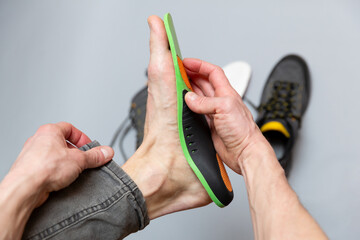 Close up of man hands fitting orthopedic insoles on a gray background. - 759564768
