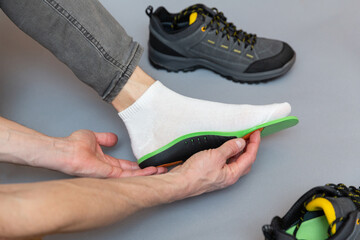 Close up of man hands fitting orthopedic insoles on a gray background. - 759564909