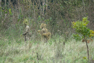 camouflage British army soldiers with guns in scrubland