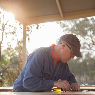 Man using chisel to smooth edges of timber