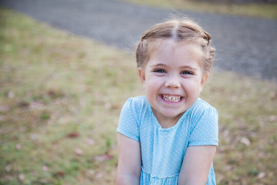 Happy little girl in blue dress smiling and looking at camera