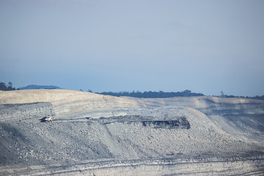 Grey open cut mine with distant dump truck