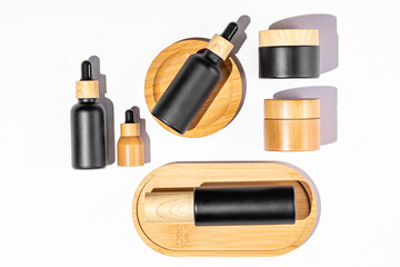 Set of cosmetic products in black and bamboo glass package. Beauty oil in dropper bottle and jars with cream for healthy skin. Unbranded package for cosmetics promotion. Knolling style, top view