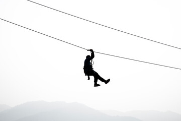 Silhouette of the person on the zip line in the sky