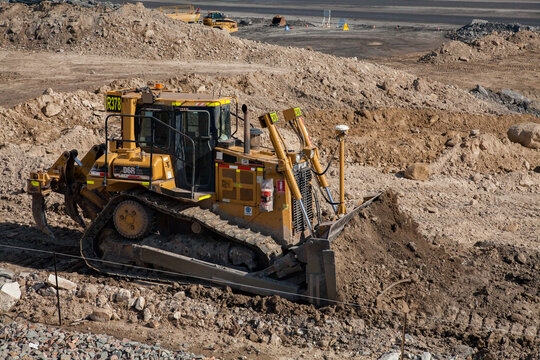Bulldozer moving dirt beside open cut mine