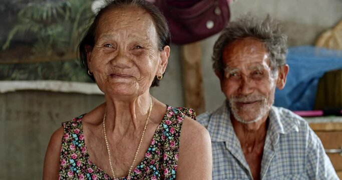 Smiling Asian man and his wife who are elderly ragpickers , while swinging a cradle to care for their infant grandchild, has a job collecting garbage and selling it, live in a slum village.