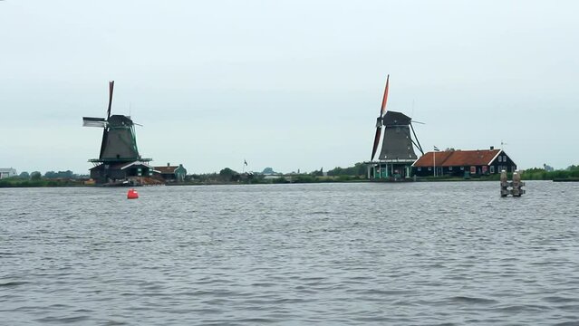 Paisaje del r&iacute;o Zaan con molino al fondo en un d&iacute;a de nublado y con viento en Zaanse Schans (Holanda)

