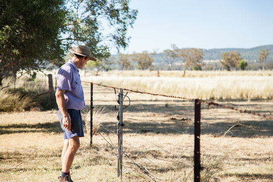 Aussie farmer checking barbed wire and electric fence on farm