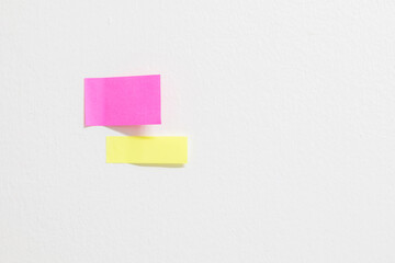 Pink paper note on a white wall background with empty space.