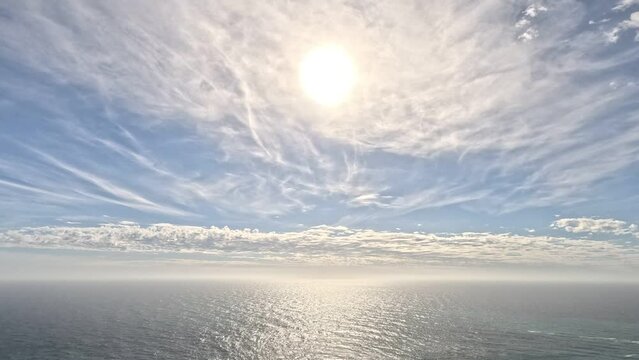 Timelapse fluffy Cirrus clouds moving in blue summer sky over calm sea. Abstract aerial nature summer ocean sunset, sea and sky view. Vacation, travel, holiday concept. Weather and Climate Change