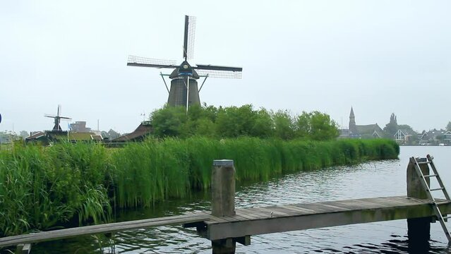Embarcadero en el r&iacute;o Zaan con molinos de viento centenarios y la ciudad holandesa de Zaandijk