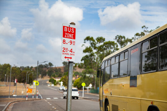 Bus zone street sign with yellow school bus beside it