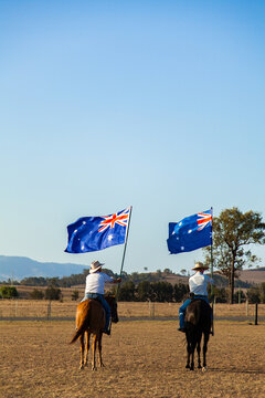 Australian stock horse riders holding flags while Advance Australia Fair national anthem is played