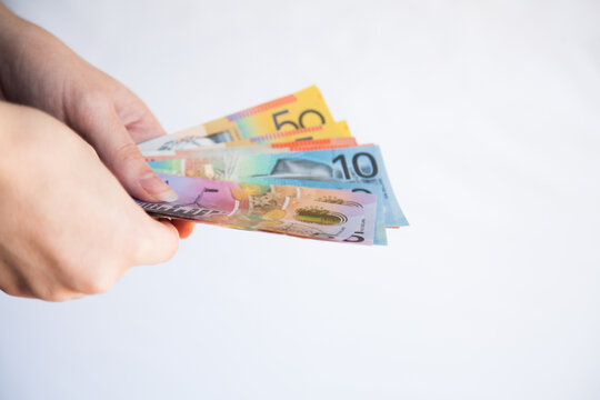 Hands holding notes of Australian money five, ten, twenty and fifty dollar notes