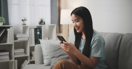 Selective focus ,Happy young woman sitting on sofa enjoy using mobile phone for online shopping cashless in living room at home - 759606557