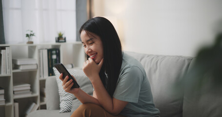 Selective focus ,Happy young woman sitting on sofa enjoy using mobile phone for online shopping cashless in living room at home - 759606587