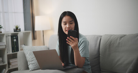 Selective focus ,Happy young woman sitting on sofa using laptop and mobile phone for online shopping in living room at home, Technology money wallet and Online payment concept - 759606589