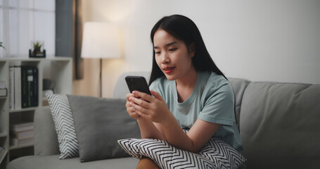 Selective focus, Selective focus, Happy young woman sitting on sofa hold a coffee mug and use...