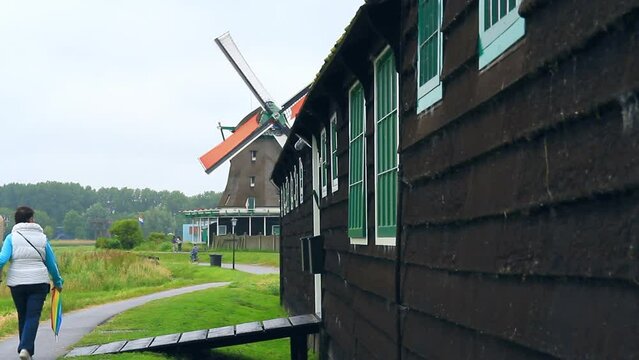 Molino de viento holandes hist&oacute;rico en pleno funcionamiento con personas paseando en Zaanza Schans 