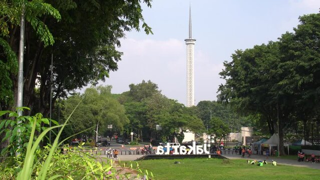 Cityscape view with Jakarta logo from behind in Banteng park. Istiqlal tower minaret building and blue skies in the background. Shot in 4k resolution.