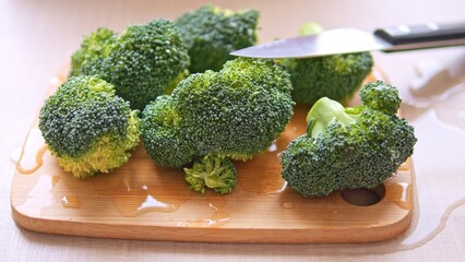 Crucifers nutritious broccoli neatly arranged on board ready for knife cutting. Perfect for health conscious creators showcasing preparation of crucifers. Witness freshness and vitality of crucifers 