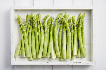 White wooden tray with fresh green asparagus