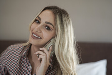 Woman with beautiful face and blonde hair speaks at smartphone