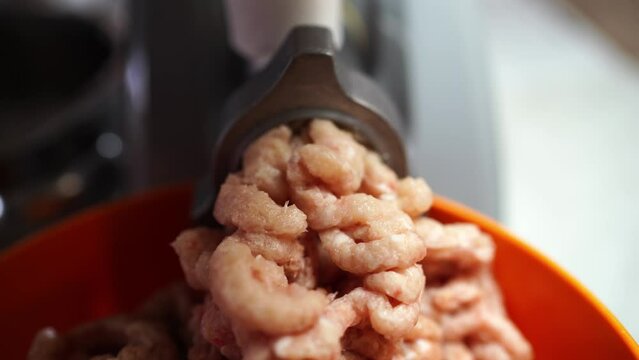 Pink minced meat comes out of the electric meat grinder mill into a bowl. High quality 4k footage