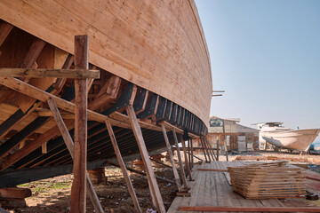Craft shipyard. Hull of yacht at wharf under construction. Low angle view of yacht frame on a...