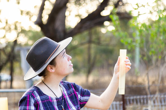 Young adult farmer measuring rain in gauge looking at sky