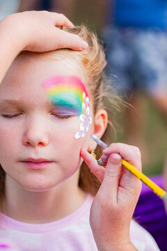 Young girl getting flowers painted on her face at party