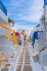 narrow side street with traditional whitewashed walls and blue accents in Mykanos Greece....