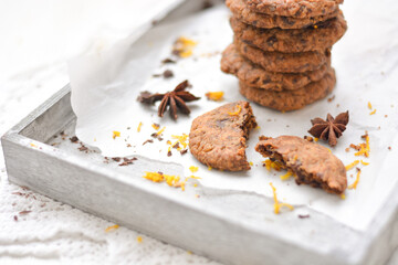 home made chocolate cookies with orange zest, chocolate chips and spices perfect for christmas on grey wooden background close up selective focus