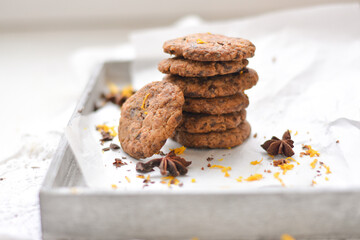 home made chocolate cookies with orange zest, chocolate chips and spices perfect for christmas on grey wooden background close up selective focus