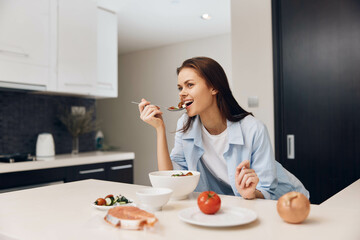 Woman enjoying a meal in a cozy kitchen setting, sitting at a table and eating from a bowl