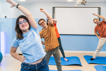 Smiling individuals with Down Syndrome enjoy a group stretching exercise.
