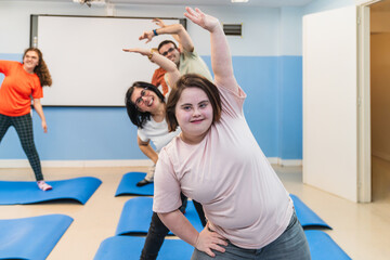 A young woman with Down Syndrome leads a joyful yoga pose with her class.