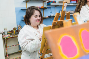 A woman with Down syndrome concentrates on her painting.