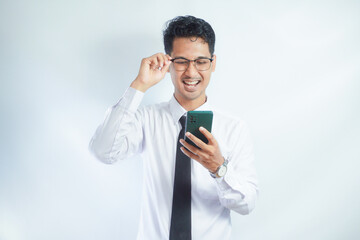 Adult Asian man laughing out loud when looking to his mobile phone
