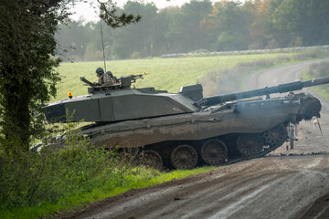 soldier commanding a Challenger 2 II FV4034 tank as it crosses over a dirt track