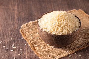 Uncooked white rice in a wooden bowl. Healthy cereal concept.  