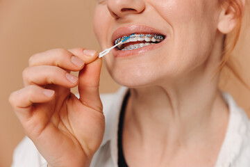 Close-up Unrecognizable woman cleans braces with a brush on beige background