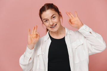 Modern happy woman showing braces on pink background, orthodontics concept